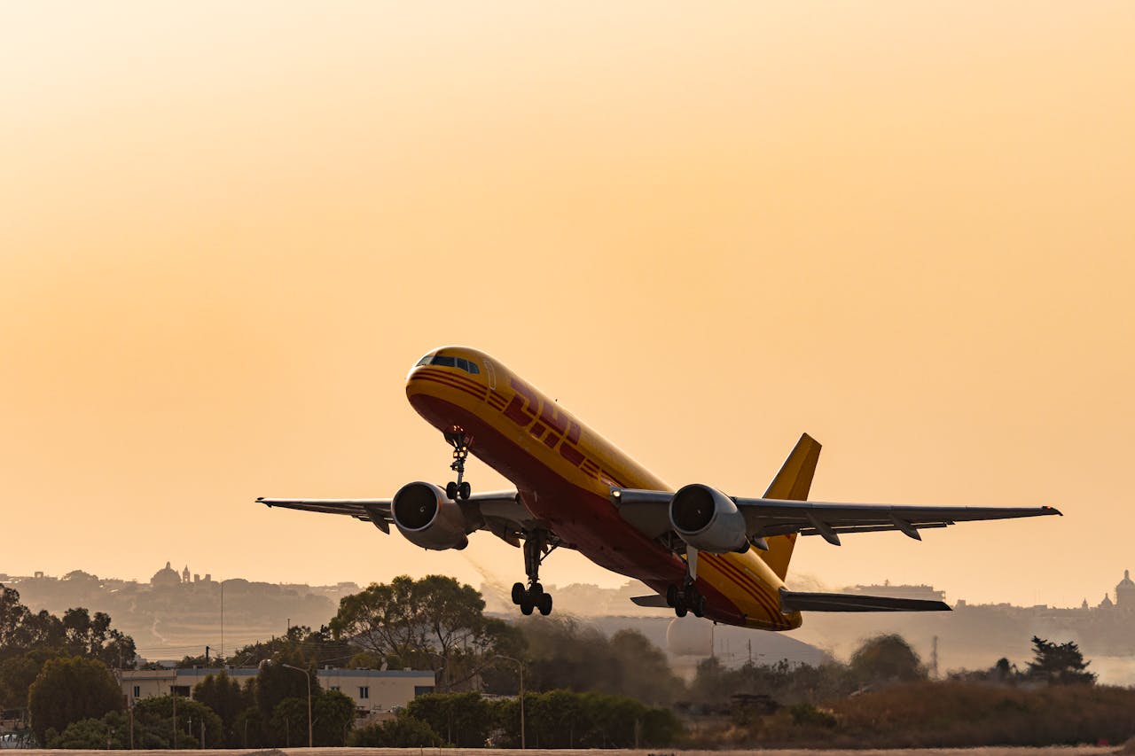 Services A DHL cargo plane takes off against a golden sunset sky, showcasing aviation in action.